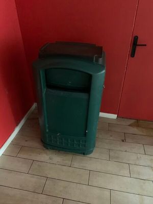une poubelle verte dans un coin d'une pièce rouge