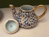 a blue and white tea pot with a lid next to a bowl