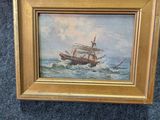 une peinture à l'huile représentant un bateau en mer, posée sur un tapis bleu