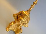 a gold figurine of an elephant holding a stick