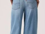 a woman in a white shirt and blue jeans stands back to back