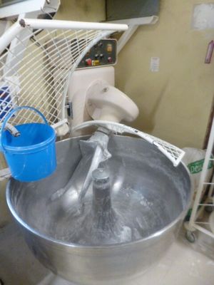 un grand saladier en métal rempli d'eau et un seau bleu