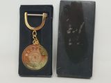 une médaille d'or dans un coffret noir avec un porte-clés en or
