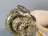 a vase that has a snake on it and a bowl in the background