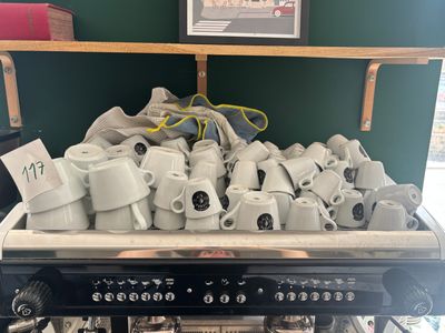 a large pile of coffee cups sitting on top of a stove