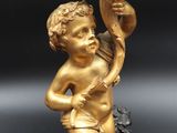 gold statue of a boy holding a flower on a rock