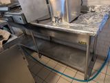 stainless steel counter top in a commercial kitchen with a blue hose attached to it