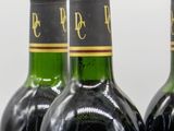 three bottles of red wine are lined up on a table