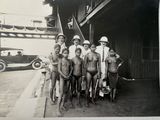 a group of naked men posing for a picture in front of a building