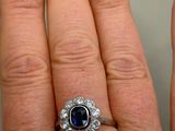 an image of a woman ' s hand holding a blue sapphire and diamond ring