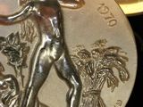 a silver coin with a picture of a man holding a baseball bat
