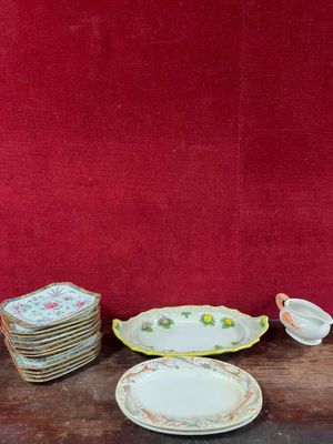 many plates and cups sitting on a table with a red wall in the background