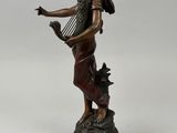 a bronze statue of a woman holding a harp on a pedestal