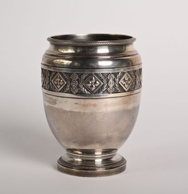 un vieux vase en argent posé sur une table blanche