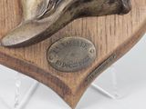 a bronze statue of a shoe on a wooden plaque