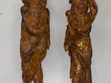 deux statues en bois représentant un garçon et une fille, posées sur une surface blanche