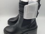 une paire de bottes noires sur lesquelles est posé un sac en plastique