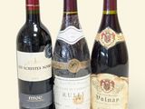 trois bouteilles de vin sont alignées sur une surface blanche