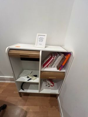 a small book shelf with books on it next to a chair