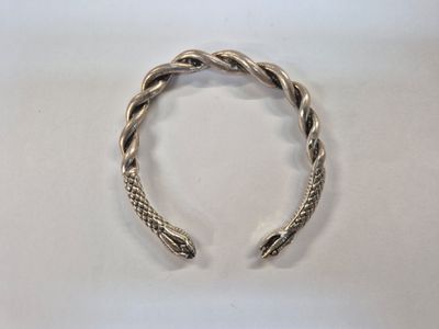 a close up of a silver bracelet on a white surface