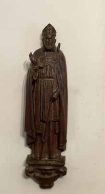statue en bois représentant un homme portant un chapeau et une cape