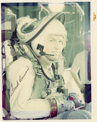 une vieille photo d'un homme en combinaison spatiale, assis sur une chaise