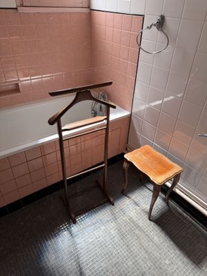 a wooden chair in the bathroom next to a bathtub