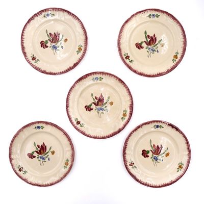 four plates with flowers painted on them sitting on a white surface