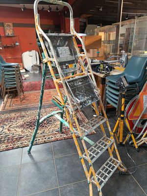 une échelle posée dans une pièce où se trouvent de nombreuses chaises
