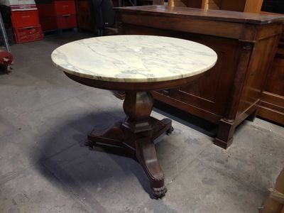 une table au plateau en marbre et au piètement en bois, dans une pièce