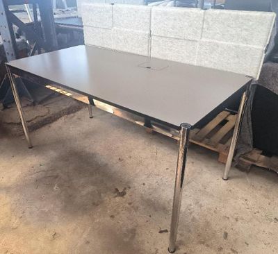 une table aux pieds chromés et au plateau blanc, placée au milieu d'une pièce