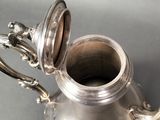 a silver tea pot with a handle on a table