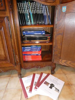 beaucoup de livres posés par terre près d'une armoire