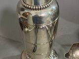 a silver vase with a spoon and a spoon rest on a table
