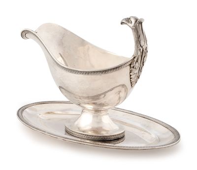 une saucière ancienne en argent posée sur un plateau orné d'un oiseau