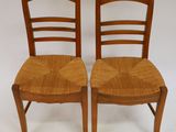 pair of wooden chairs with woven seats against a white background