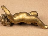 a gold statue of a baby laying down on the ground