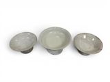 three gray bowls sitting next to each other on top of a white surface