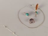 deux bagues et un collier posés sur une surface blanche
