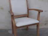 une chaise en bois avec une assise rembourrée blanche, placée contre un mur