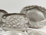 a group of silver dishes sitting on a white surface