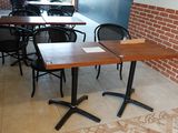 tables and chairs in a restaurant with a brick wall in the background