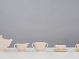several cups and saucers are lined up on a white table