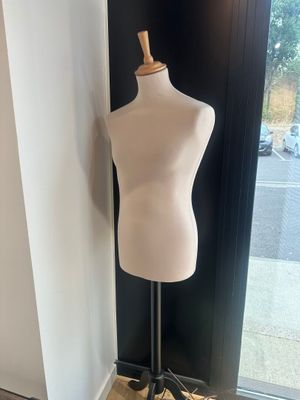le mannequin est assis sur un socle devant une vitrine