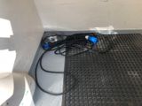 wires are plugged into the floor of a bathroom with a toilet in the background