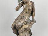 an antique bronze statue of a woman sitting on a tree stump