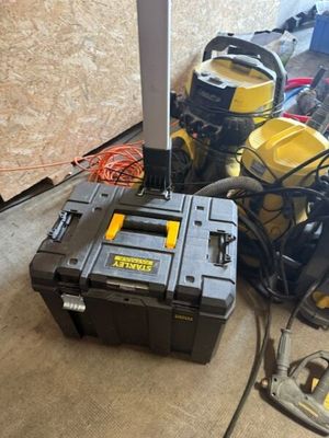 Des outils jaunes et noirs sont posés par terre dans une pièce