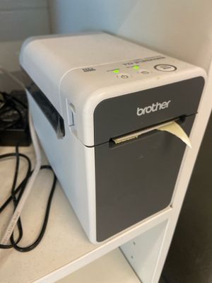 une petite imprimante posée sur une étagère à côté d'un téléphone
