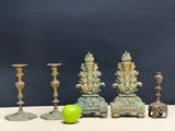 three antique brass candlesticks and a green apple on a table