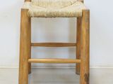 an image of a wooden stool with a woven seat on it
